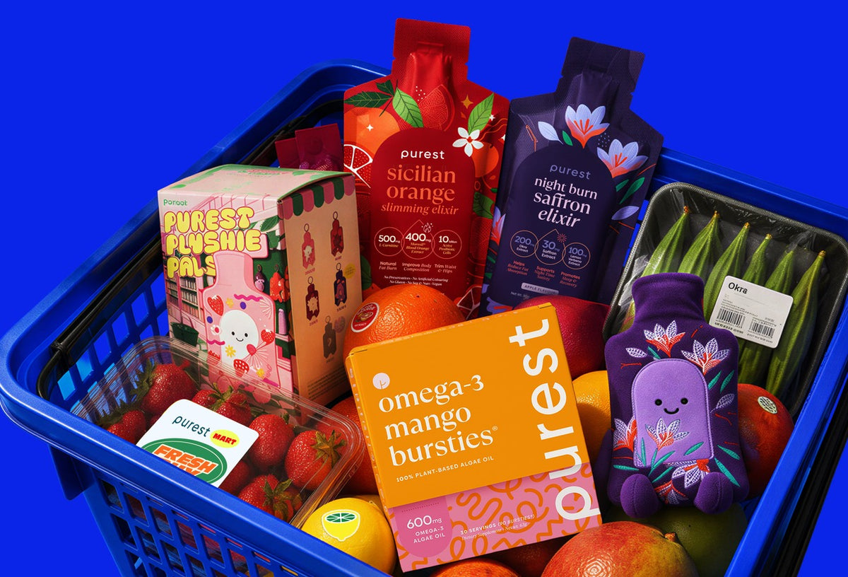 A Purest Mart shopping basket with Sicilian Orange Slimming Elixir, Night Burn Saffron Elixir, Omega-3 Mango Bursties, Purest Plushie Pals and fresh fruit